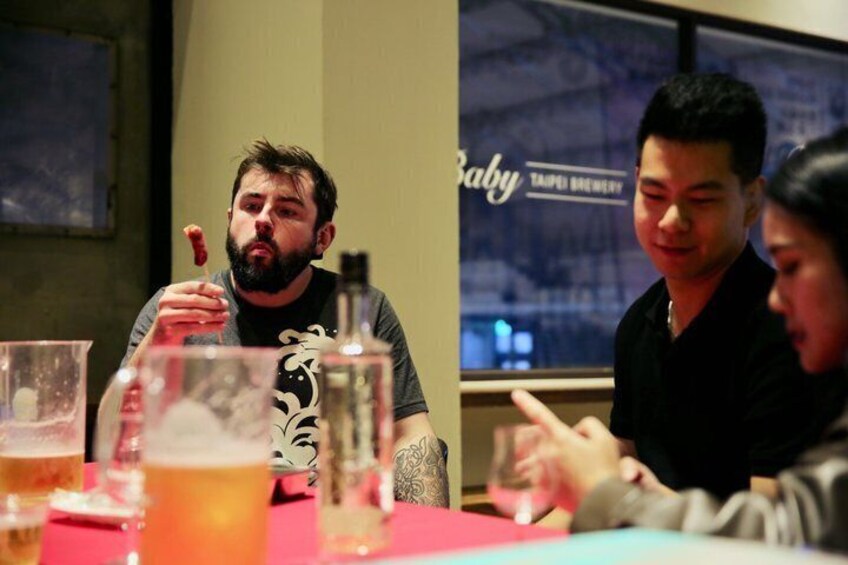 A group of people sitting at a table with drinks and a bottle. 3