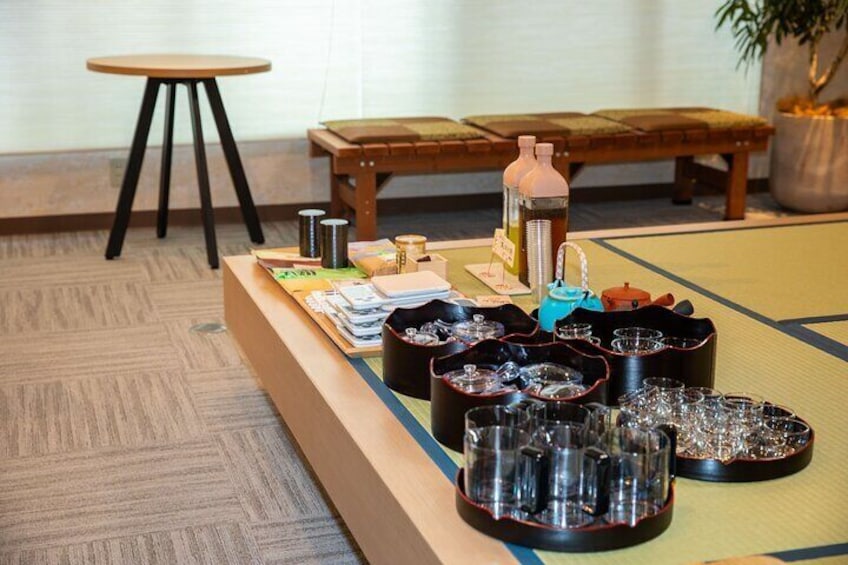 A tatami mat room with a low table set with sake bottles, glasses, and a teapot. 5
