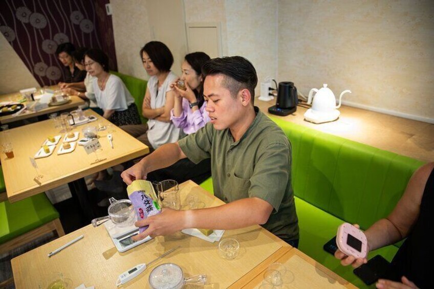 A person pouring a drink into a glass at a restaurant table. 2