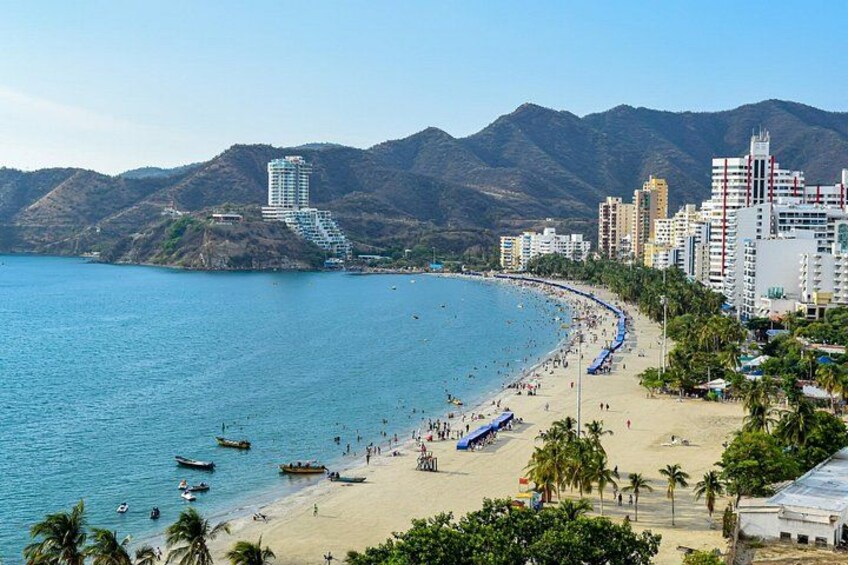 A coastal cityscape with a beach, boats, and mountains in the background. 2