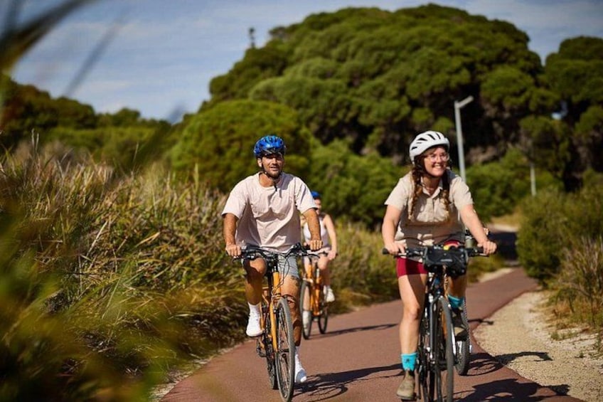 Two cyclists on a paved path surrounded by greenery. 2