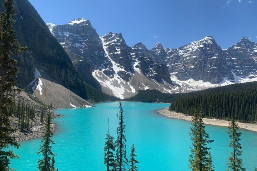 A turquoise lake surrounded by snow-capped mountains and dense forests. 5