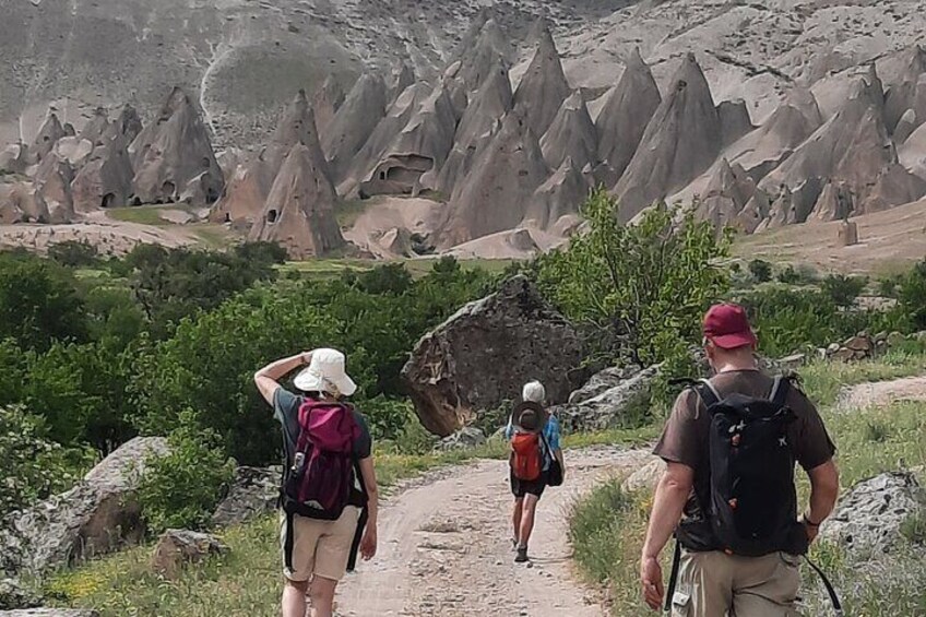 Un grupo de excursionistas en un sendero de tierra con un paisaje montañoso al fondo. 2