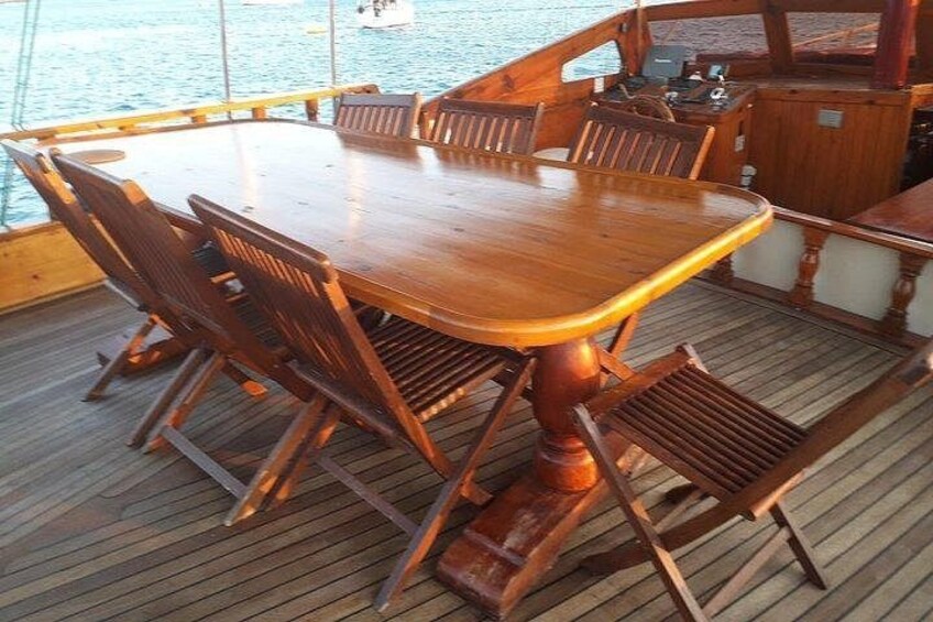 Een houten tafel en stoelen op het dek van een boot. 4