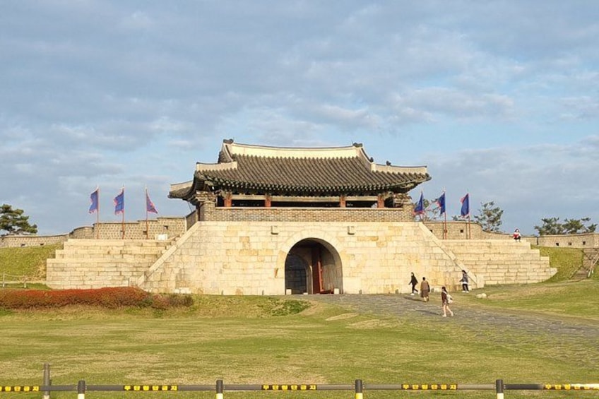 A traditional Korean gate with a tiled roof, stone steps, and flags. 2