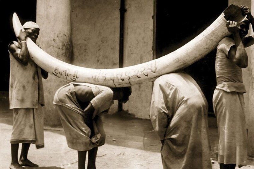 Three men carrying a large, curved object. 3