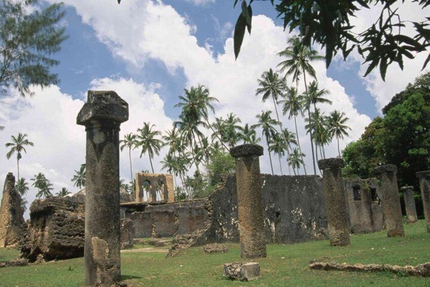 Ancient stone ruins with columns, surrounded by palm trees and a clear sky. 4