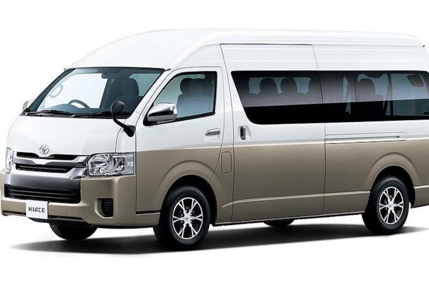 A beige Toyota Hiace van with alloy wheels and a visible license plate. 2