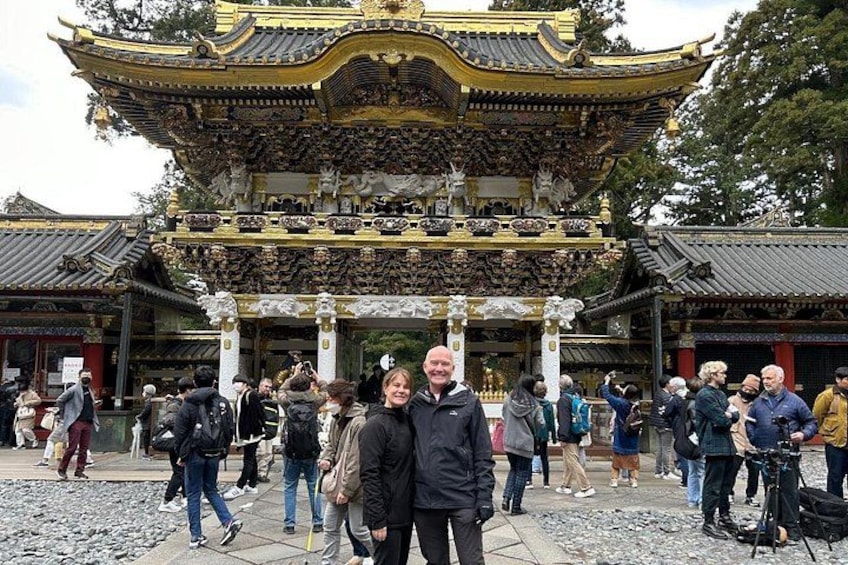 A traditional Chinese gate with intricate carvings and a golden roof, surrounded by visitors. 1