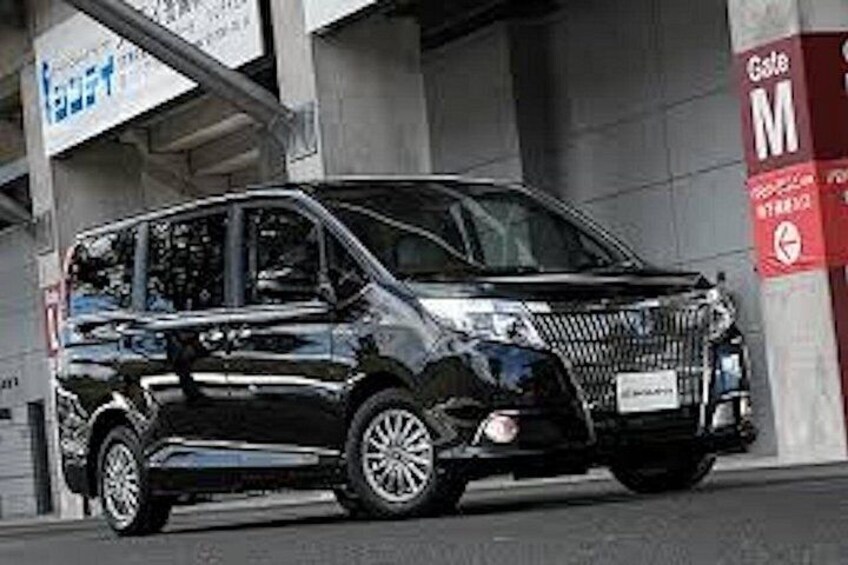 A black minivan parked in front of a building with a sign that reads 'Gate M'. 5