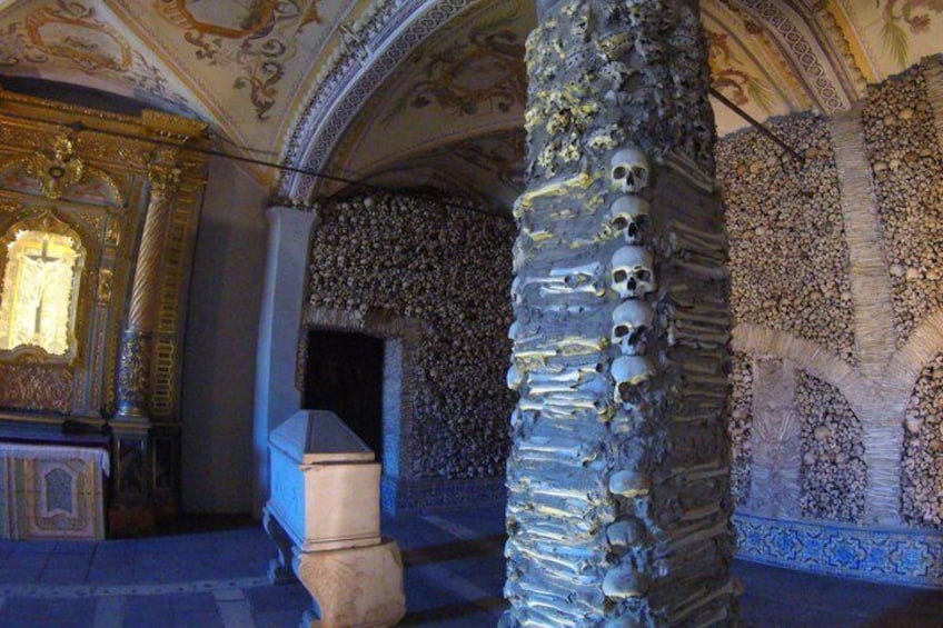 Una columna de piedra con calaveras, techo ornamentado y una ventana iluminada. 4