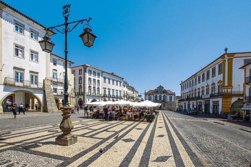 Una calle empedrada con cafés al aire libre, edificios históricos y un farol. 2