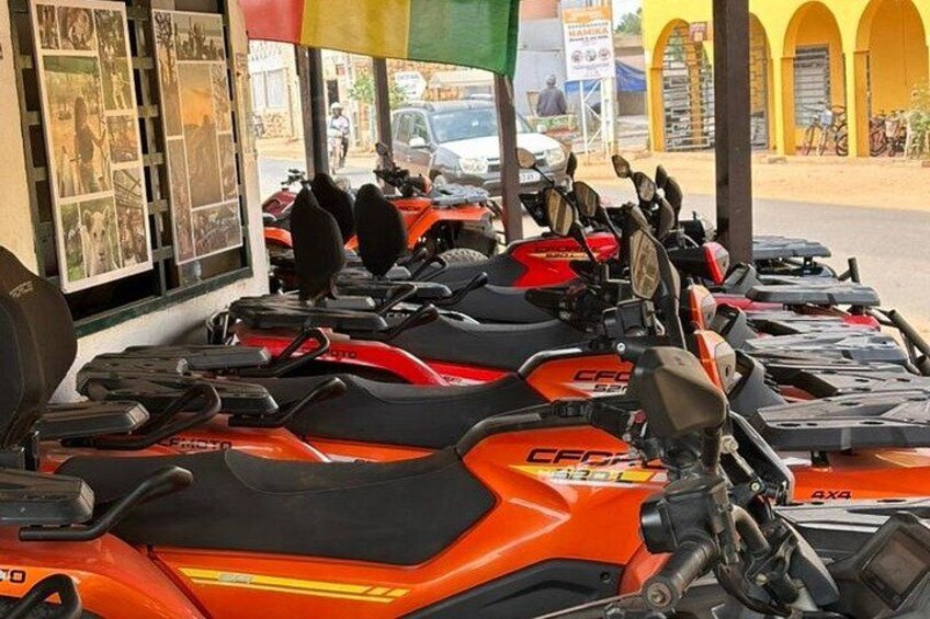 A row of orange motorcycles parked under a shelter. 2