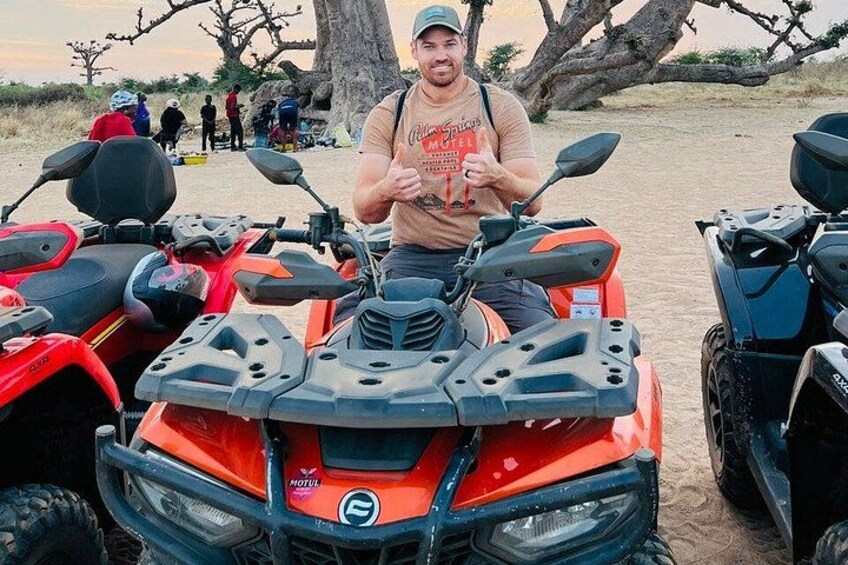 A person sitting on an orange ATV with a desert landscape in the background. 4