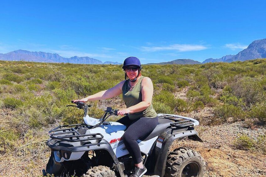 A person riding an ATV in a desert landscape with mountains in the background. 2