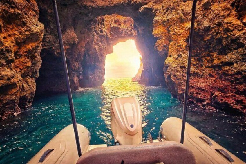 A boat in a rocky cove with a view of the sea through a natural arch. 3