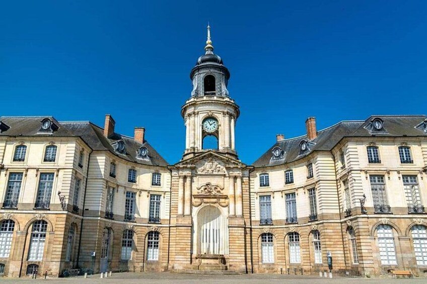 A historic building with a clock tower, large arched windows, and a central entrance. 5