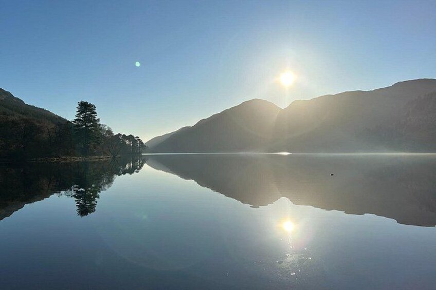 A calm lake reflecting the sun and mountains. 4