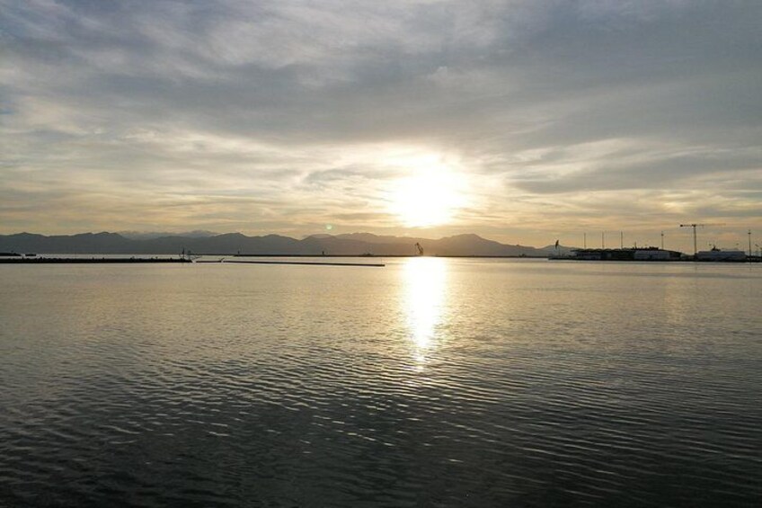 Acqua calma che riflette il sole, con montagne in lontananza e un cielo nuvoloso. 5