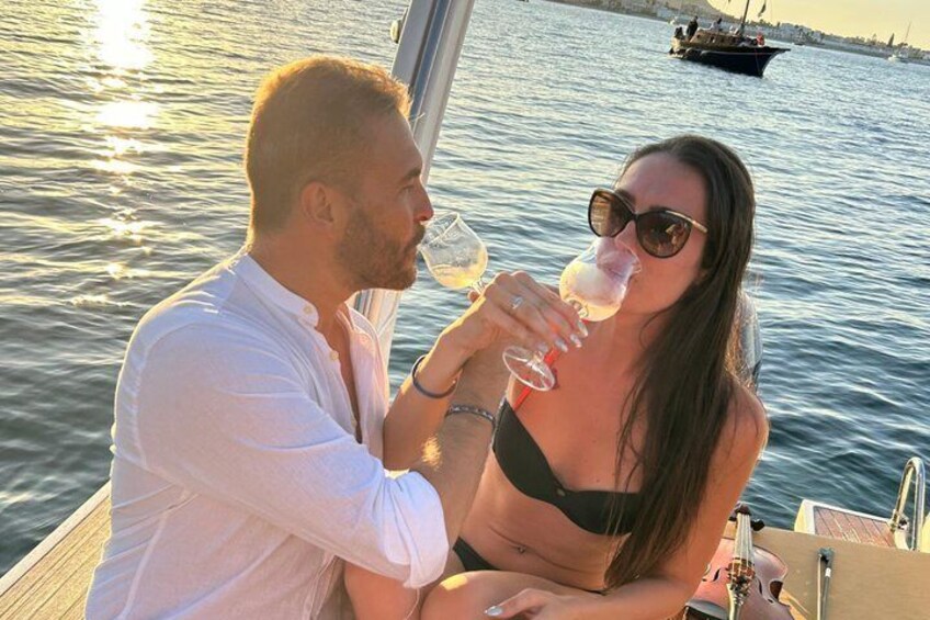 Two people on a boat, one holding a glass. 2