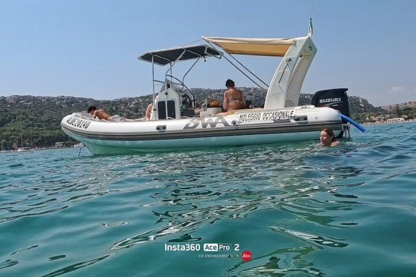 A small boat with people on it, a Suzuki motor, and a person swimming nearby. 3
