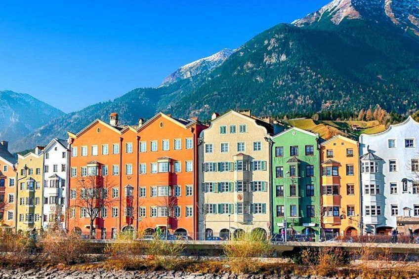 Colorful buildings along a river with mountains in the background. 1