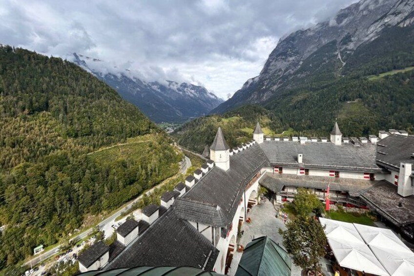 A mountainous landscape with a building featuring steep roofs and multiple towers. 4