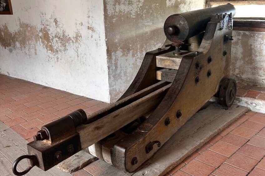 An old cannon mounted on a wooden carriage with wheels. 3