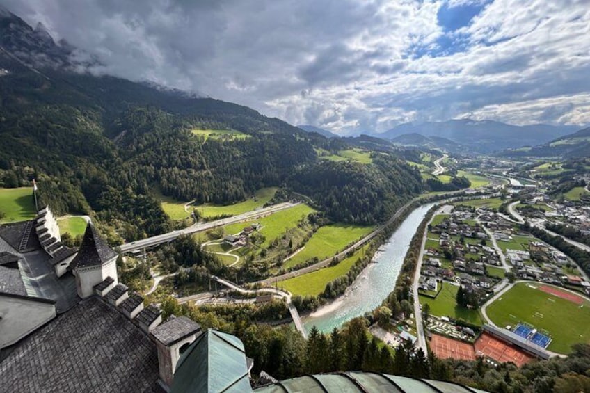 A river winding through a valley with a castle on a hill, surrounded by green fields and a town. 2