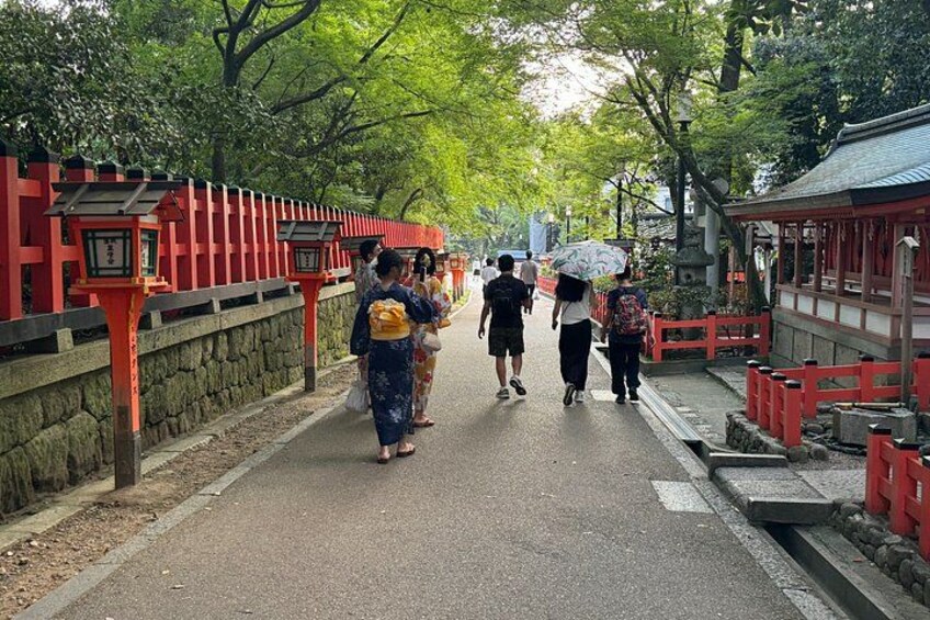 A pathway lined with red lanterns, a stone wall, and traditional Japanese architecture. 5