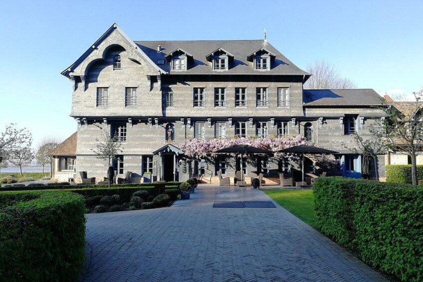 A large, historic building with a symmetrical facade, a central entrance, and a well-maintained garden with a pathway leading to the entrance. 4