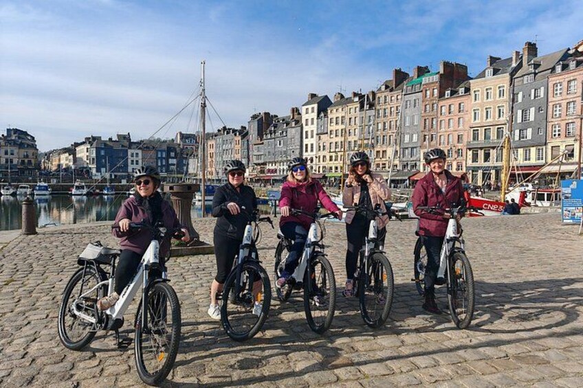 A group of people on bicycles by a waterfront with buildings in the background. 5