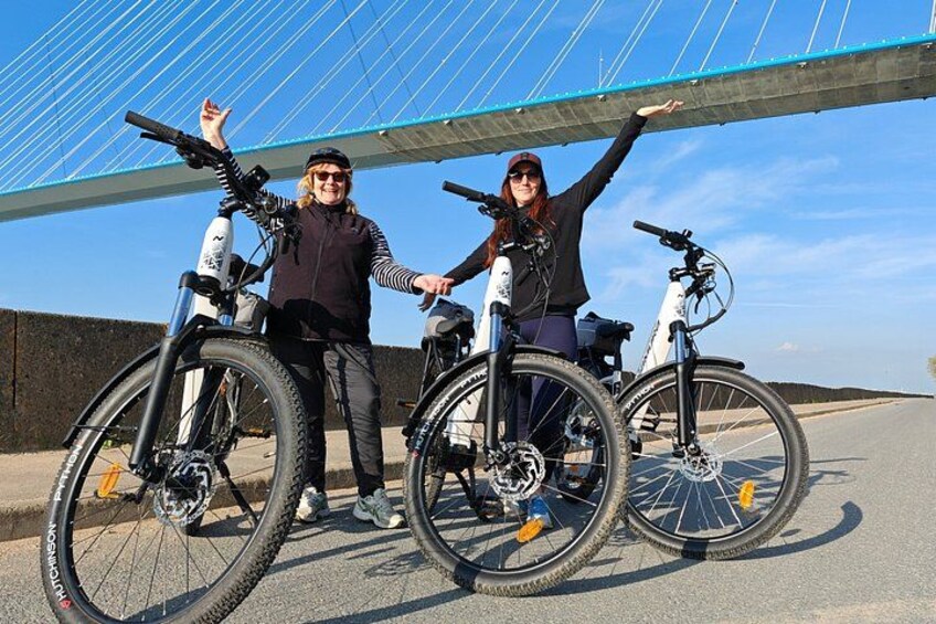 Two people with bicycles in front of a bridge. 2
