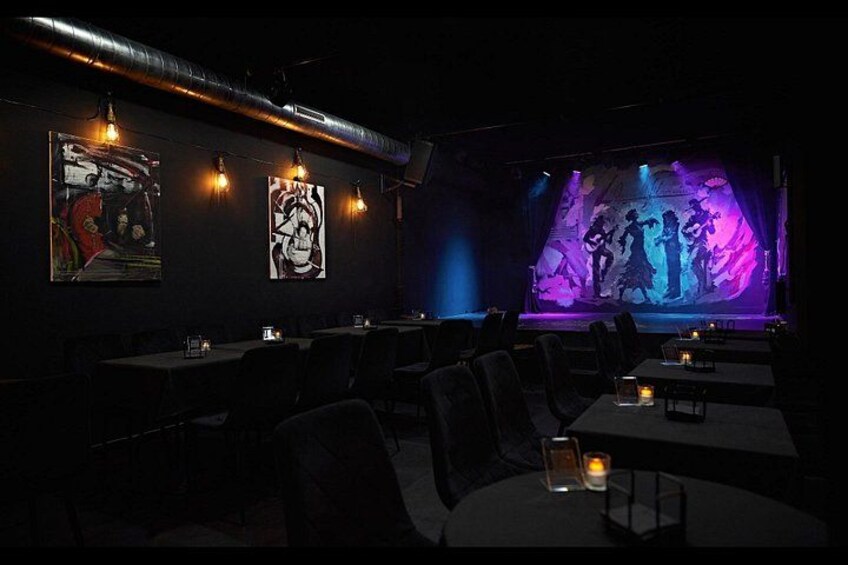 A dimly lit restaurant with tables, chairs, and wall art. 1