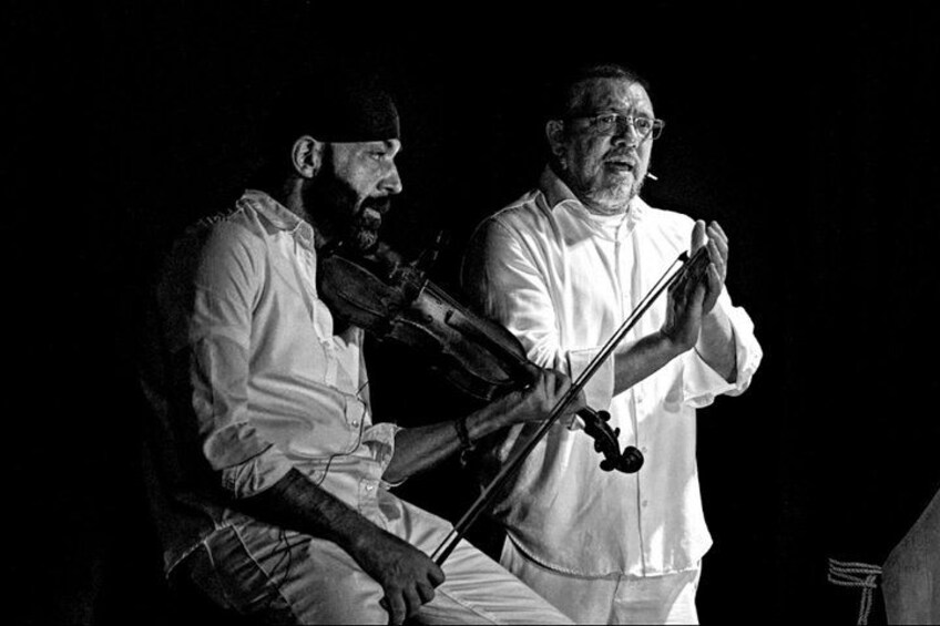 Two individuals playing string instruments on stage. 2