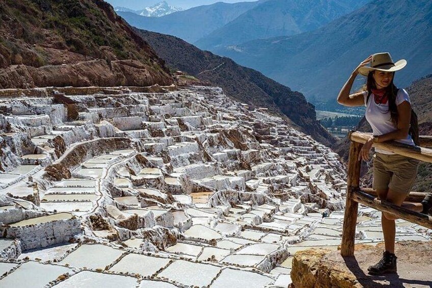 Terraced stone structures, a person standing on a wooden railing, and a mountainous landscape in the background. 1