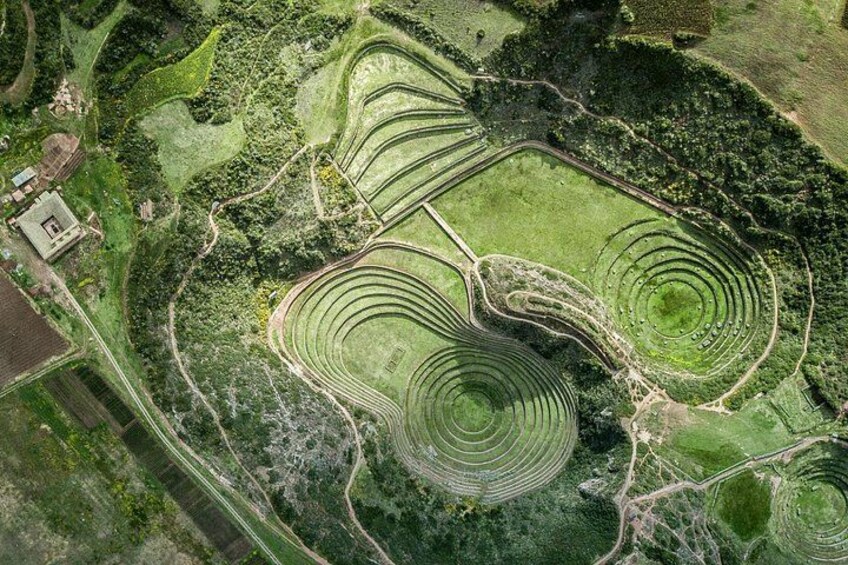 A large agricultural field with circular crop patterns, a small building, and surrounding greenery. 4
