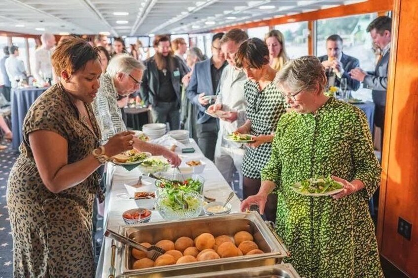 Un bufé con alimentos y personas sirviéndose. 3