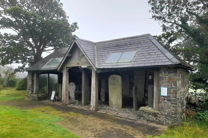 A stone building with a sloped roof and a signboard. 3