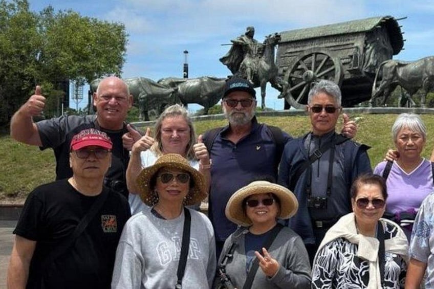 A group of people posing in front of a historical monument with a large cannon and a carriage. 3
