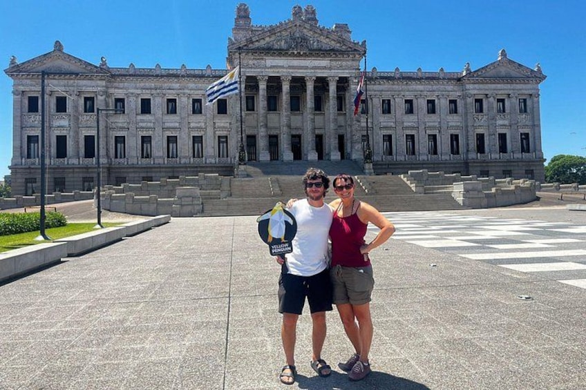 A large neoclassical building with columns and a flag. 1