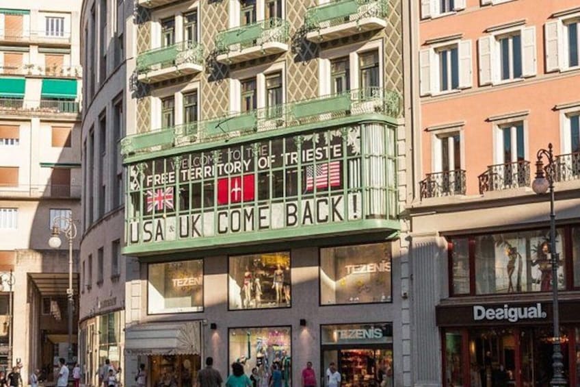 A theater marquee with 'USA & UK COME BACK!' and 'FREE TERRITORY OF TRIESTE' text. 1