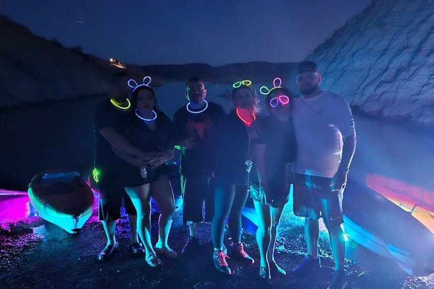 A group of people at a nighttime outdoor event with colorful lights and a rocky landscape in the background. 2