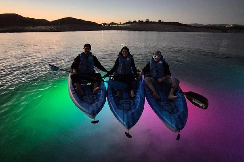 Three people kayaking on a calm body of water at dusk. 4
