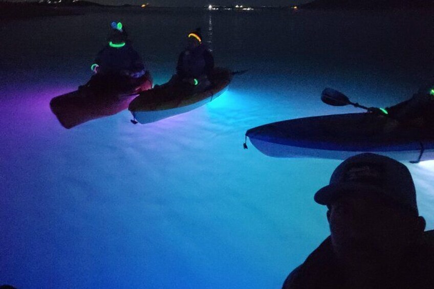 Two kayaks on a frozen body of water at night with people in them. 2