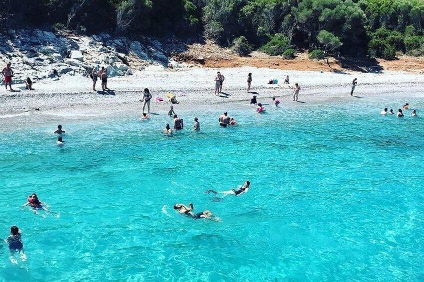 Una playa con gente nadando y caminando en el agua. 4