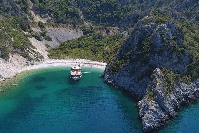 Un barco en un mar turquesa rodeado de acantilados rocosos y vegetación. 3