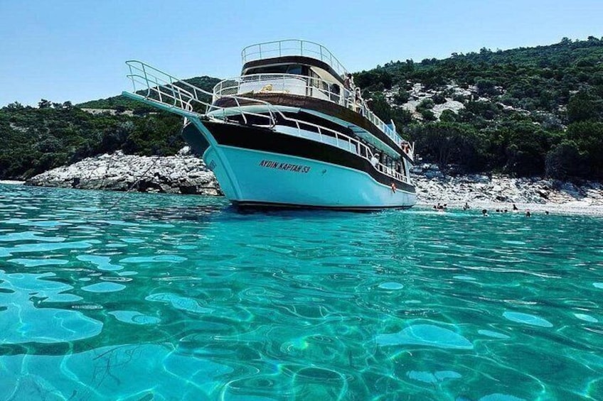 Un barco llamado 'AETON CAPTAIN' fondeado cerca de una costa rocosa con agua turquesa cristalina. 5