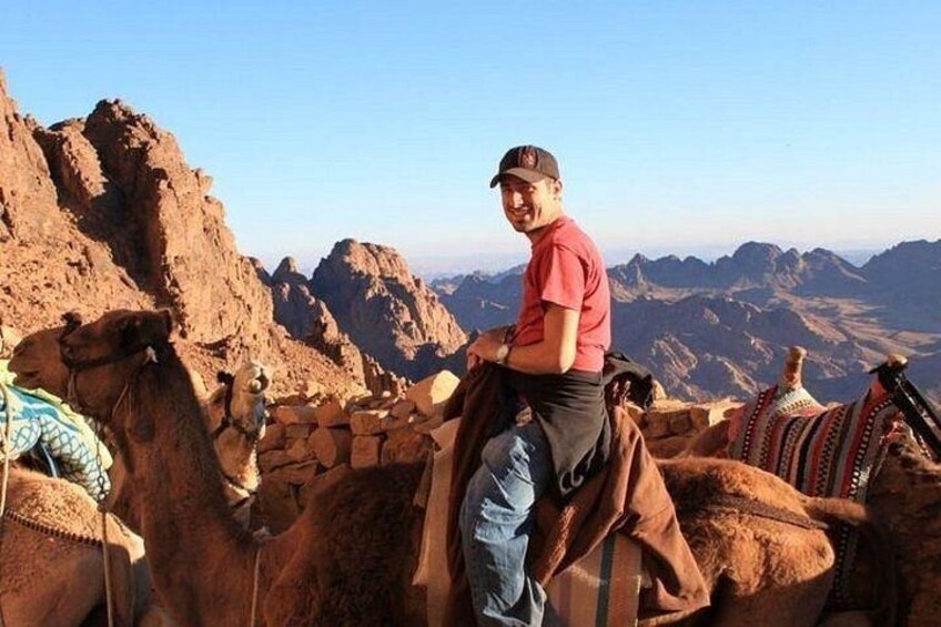 A person riding a camel with a mountainous landscape in the background. 4