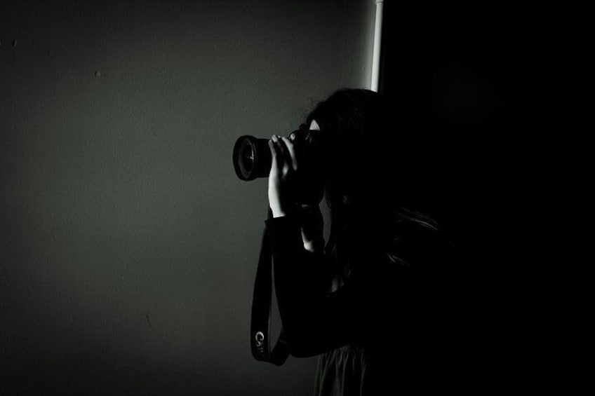 A person holding a camera, possibly taking a photo, with a dark background. 5